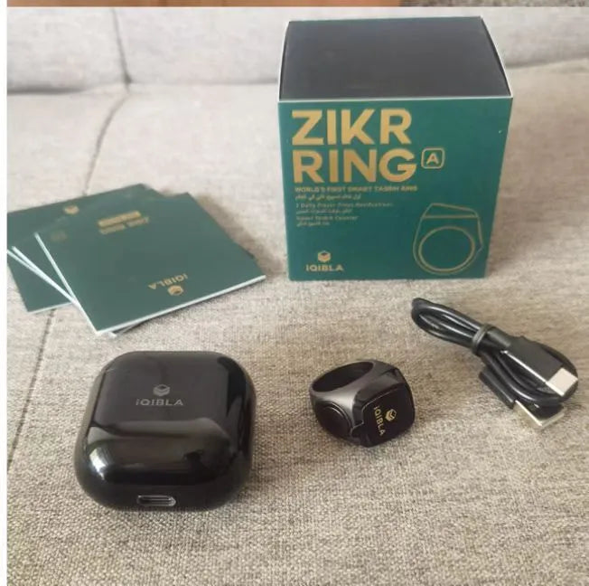 Zikr1 smart ring in black, green, rose gold, or silver on charging case with OLED display showing dhikr count.