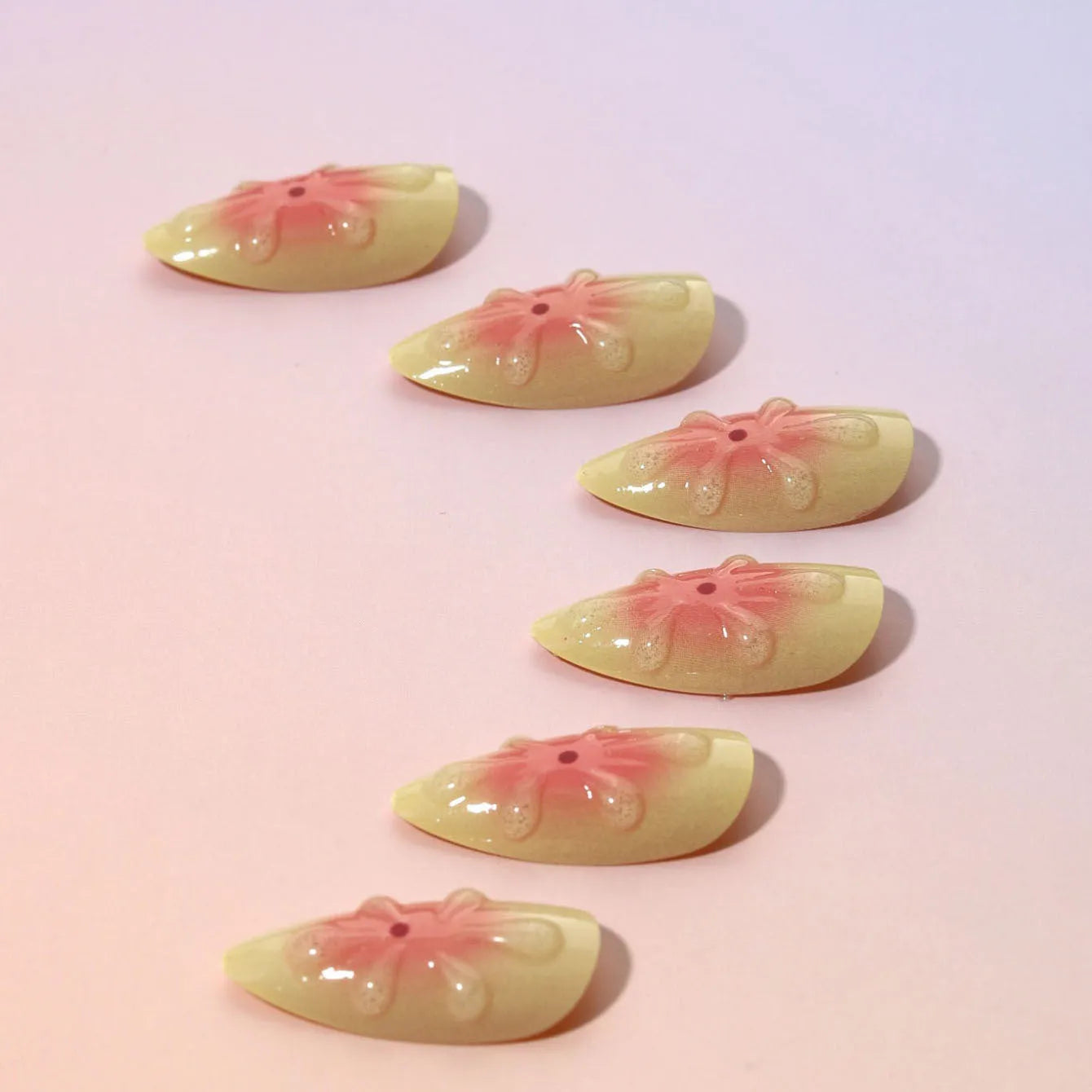 Cartoon-style plastic fake nails with 3D raised pink flowers, shown with jelly glue and a nail file.