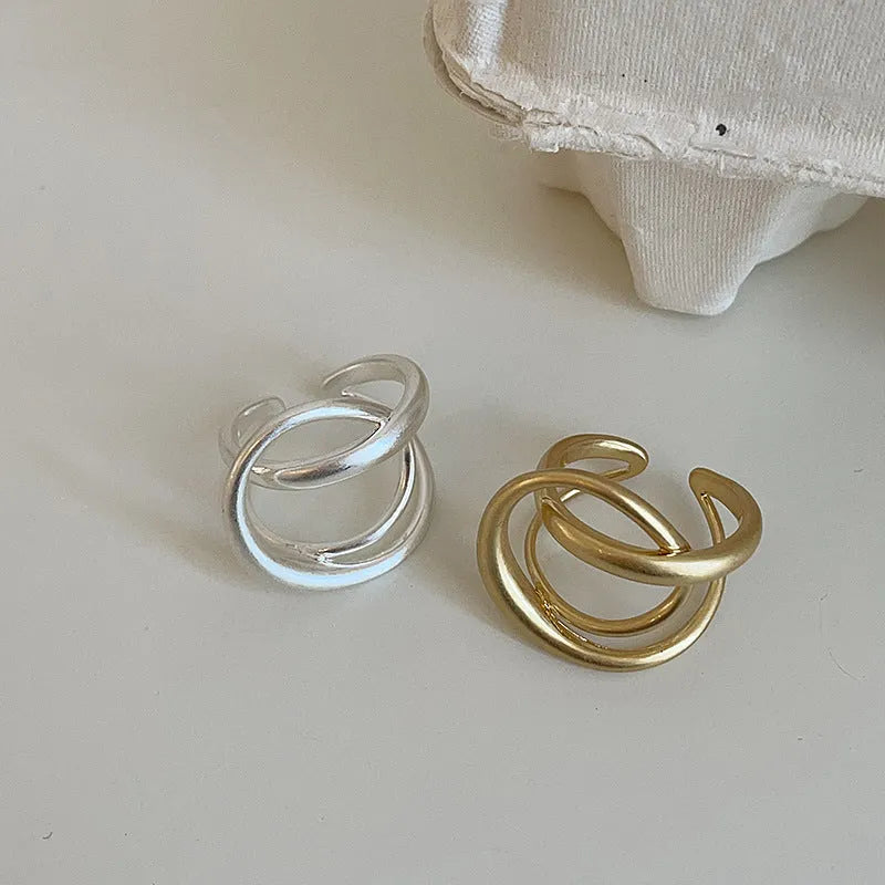 Geometric open ring for women with 3D interlaced matte metal design in gold or silver.