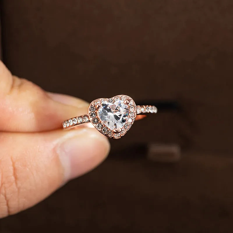 Close-up of a women's heart-shaped ring with a clear crystal centre in rose gold or silvery finish.