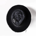 Handmade wool felt skull hat with a conical crown on a neutral background