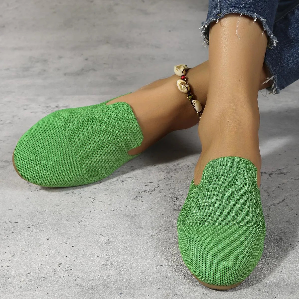 Apricot coloured mesh slip-on sandals with a round toe and flat rubber sole on a wooden floor.