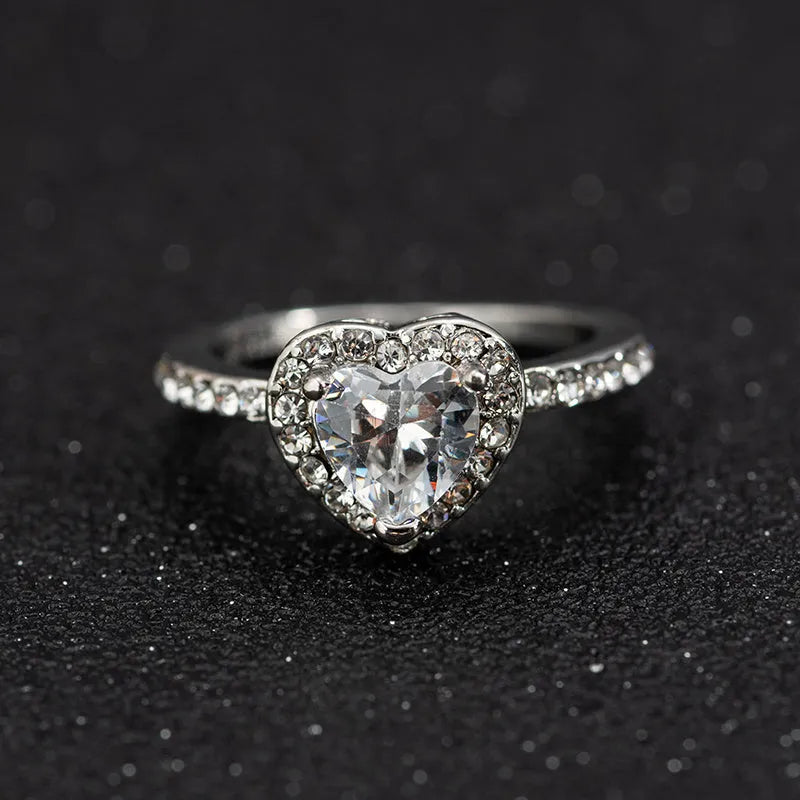 Close-up of a women's heart-shaped ring with a clear crystal centre in rose gold or silvery finish.