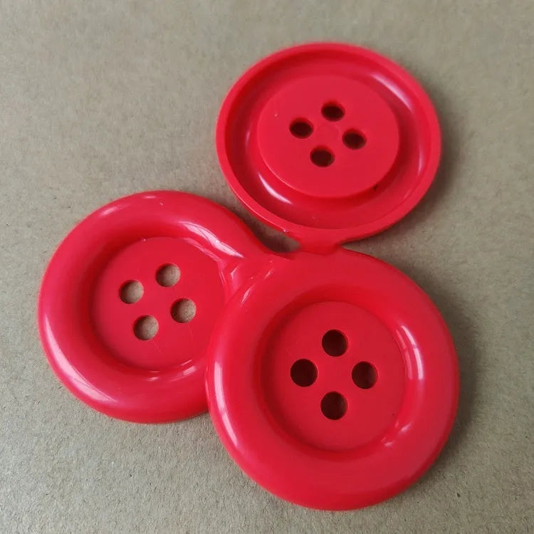 Oversized round plastic button with four holes in various colours and sizes from 38mm to 70mm.