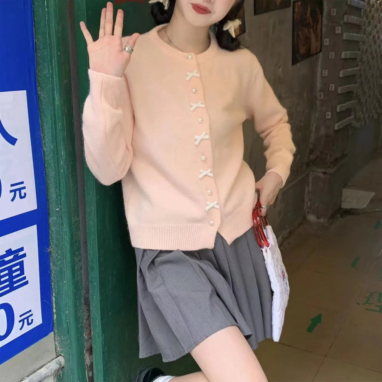 Women's solid colour cashmere cardigan with bow detail and pearl buttons on a hanger