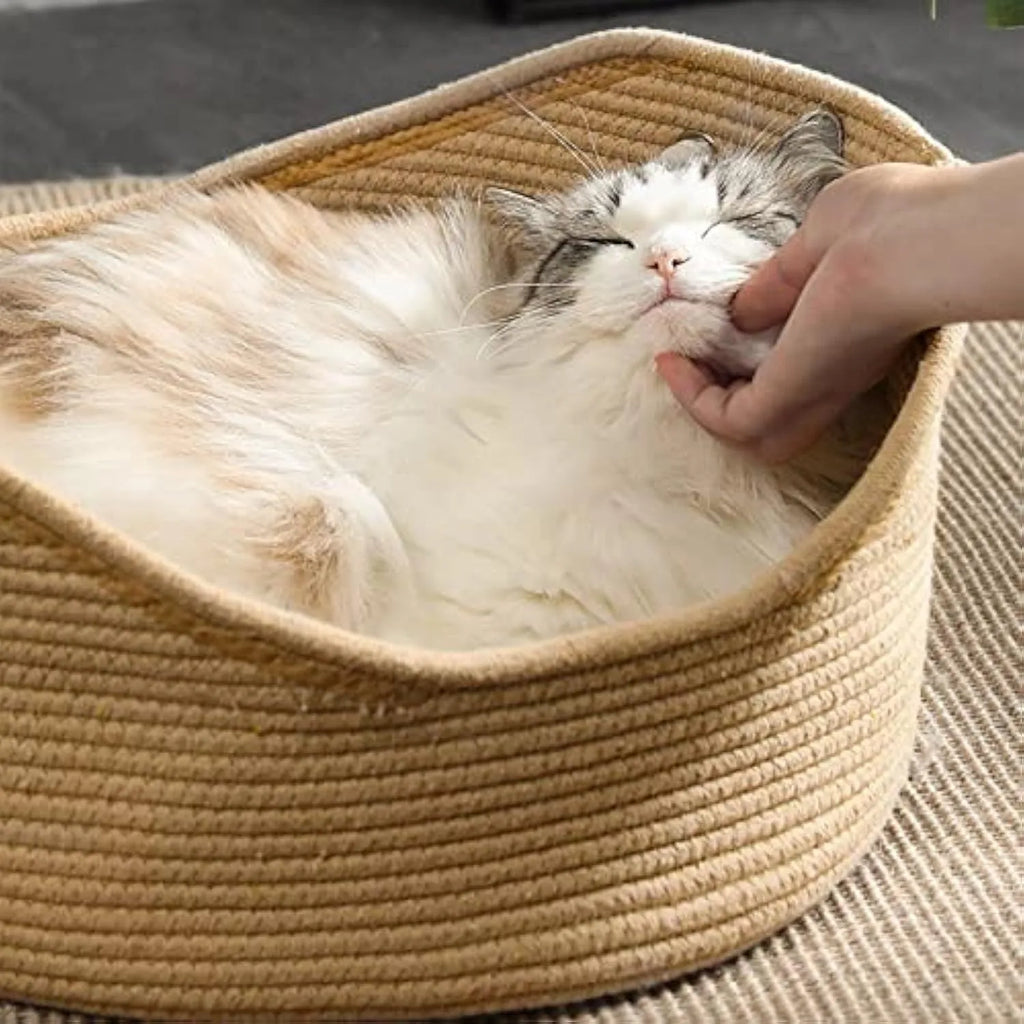 A rectangular wicker cat bed basket with a corrugated cardboard scratching surface on its side.