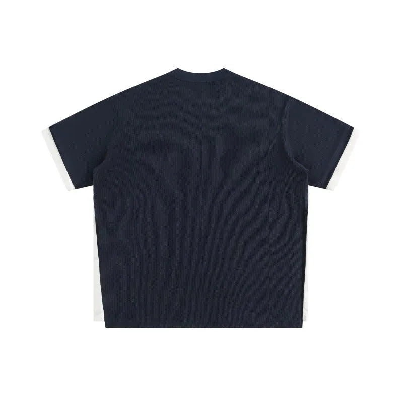 Loose grey waffle-textured t-shirt with embroidered retro lettering on the chest.