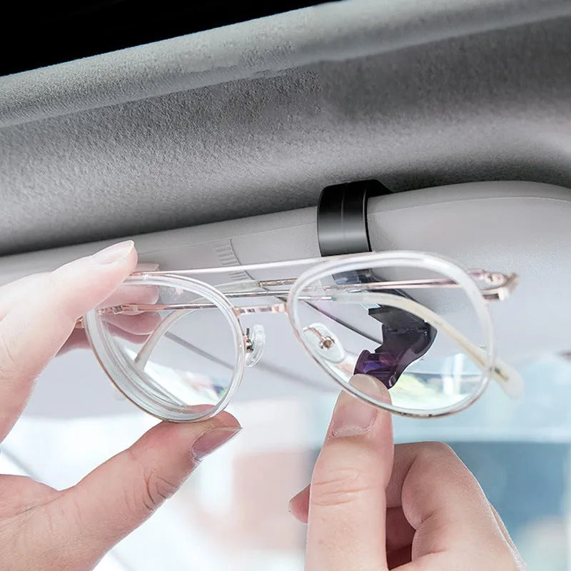 Black plastic clip for holding glasses and cards on a car sun visor.
