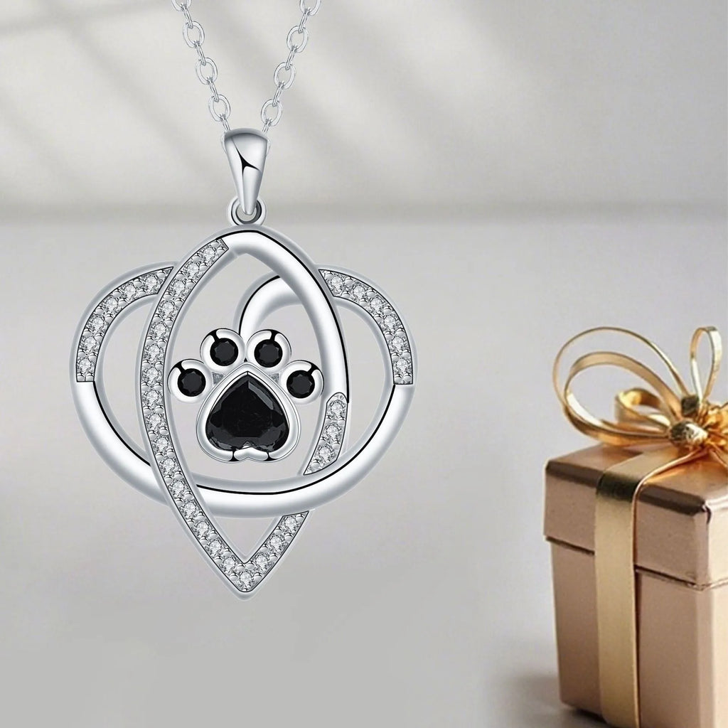 Close-up of a copper necklace pendant showing detailed dog and cat paw prints on a cross chain.