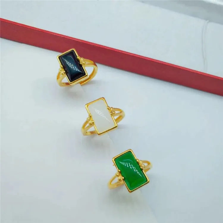 Adjustable brass gold-plated ring with a centre gemstone, shown in black, green, and white colour options.