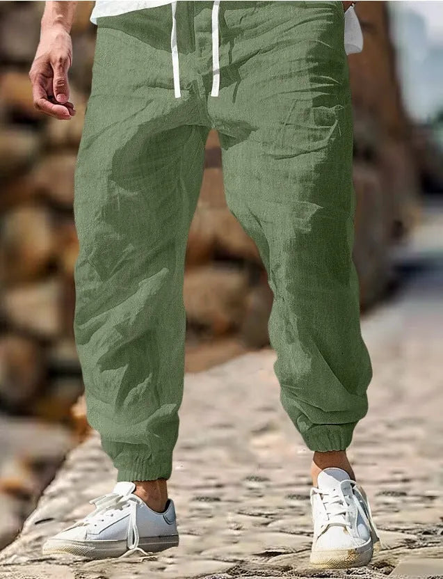 Men's beige straight leg linen trousers with elastic waistband laid flat
