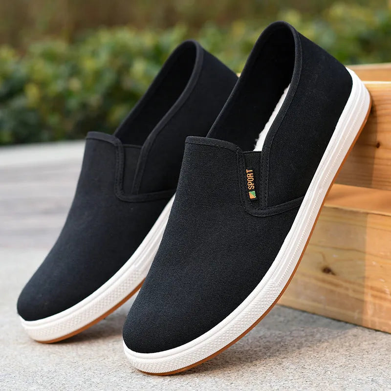 Men's black low-top slip-on canvas shoes with a round toe and composite sole on a white background.