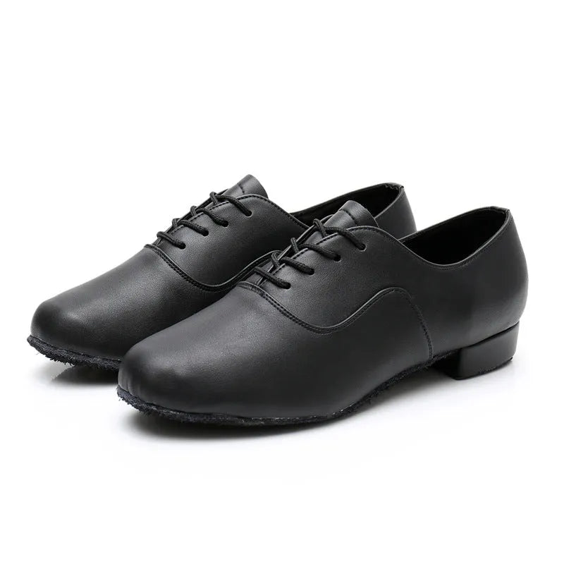 Men's black dancing shoes with a synthetic leather upper and calf leather sole, shown on a studio floor.