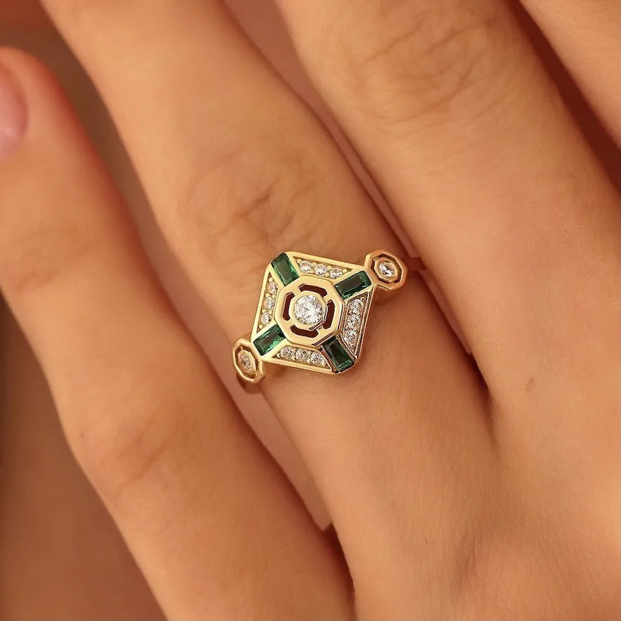Women's square geometric fashion ring with a green emerald-coloured stone on an electroplated band.
