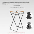 Black iron folding storage rack with a wooden handle for hanging outdoor waste bags.