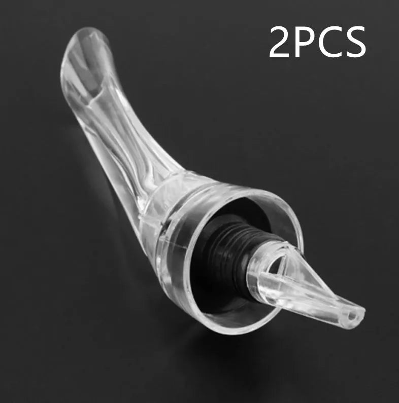 Compact clear acrylic wine aerator with a stainless steel filter insert on a wooden table.
