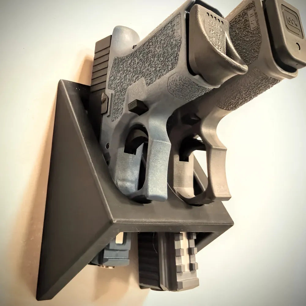 Black punk-style plastic pistol stand for airsoft and display models, measuring 10.85 by 7.6 cm.