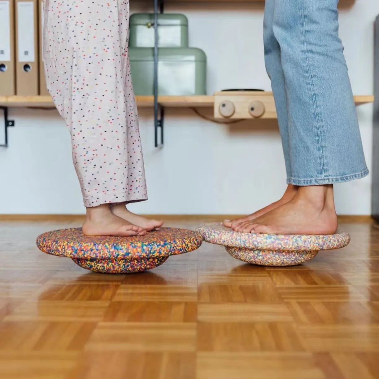 A plastic balance board for children, shown in mixed wood colour and solid black options.