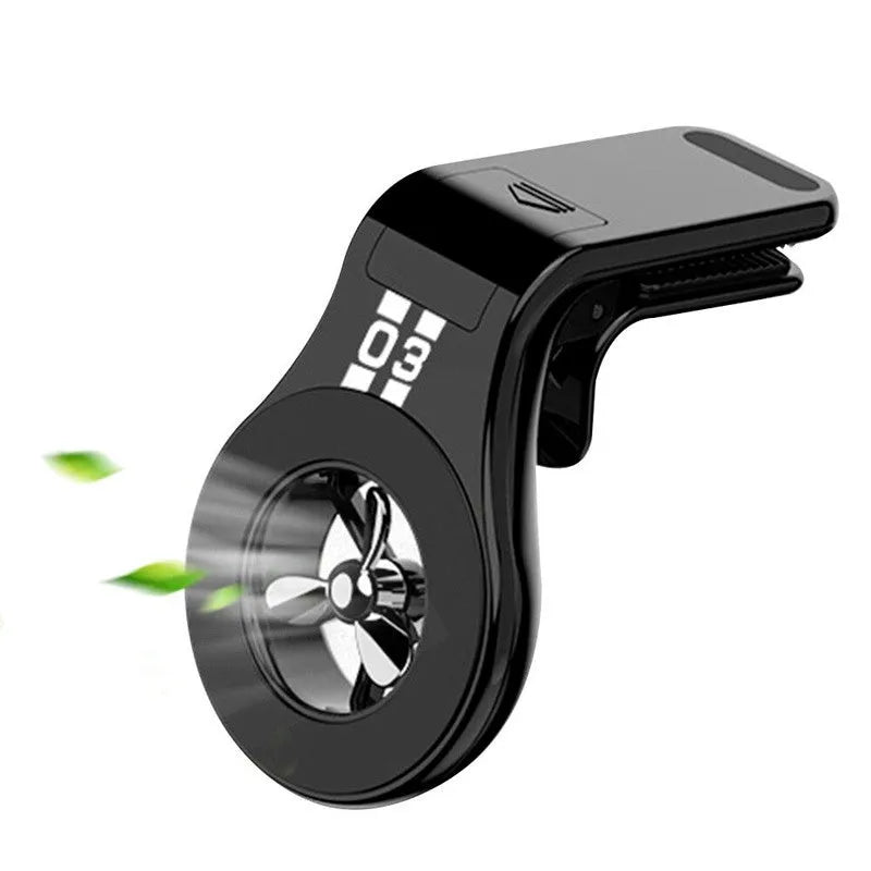 Black magnetic car phone holder clipped to a car air vent, showing a smartphone attached and the included fragrance slice.