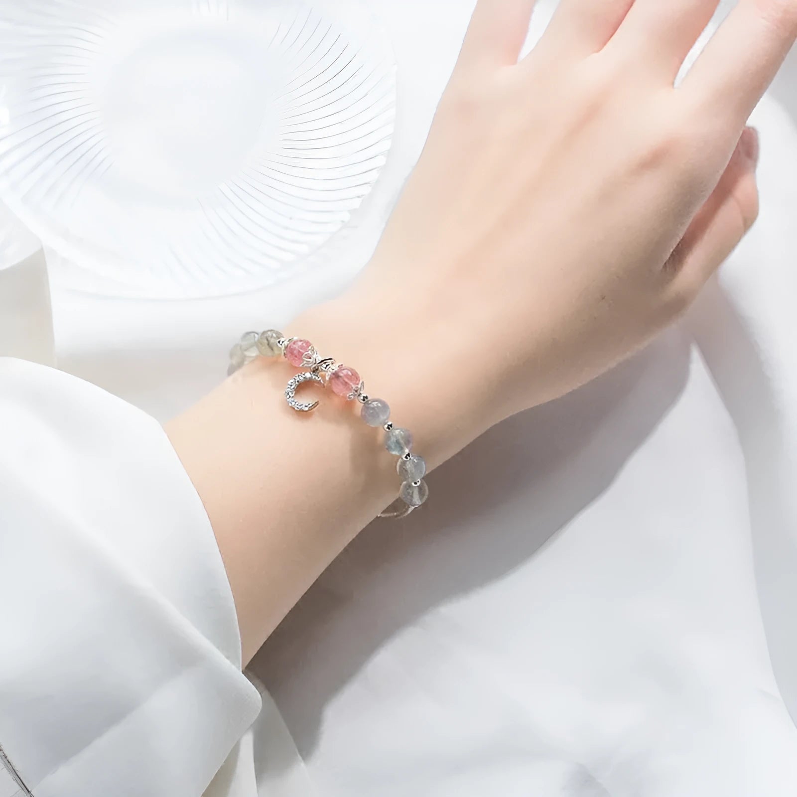 Handmade adjustable moonstone bracelet with crescent moon charm and crystal bead on wrist.