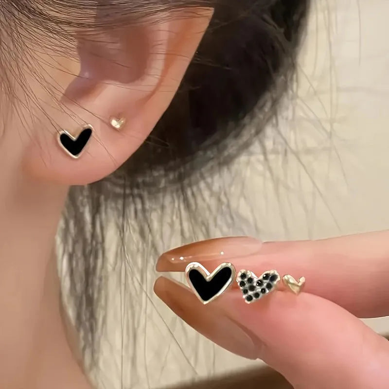 Three pairs of women's heart-shaped alloy earrings in gold, black, black-white, and pink colours