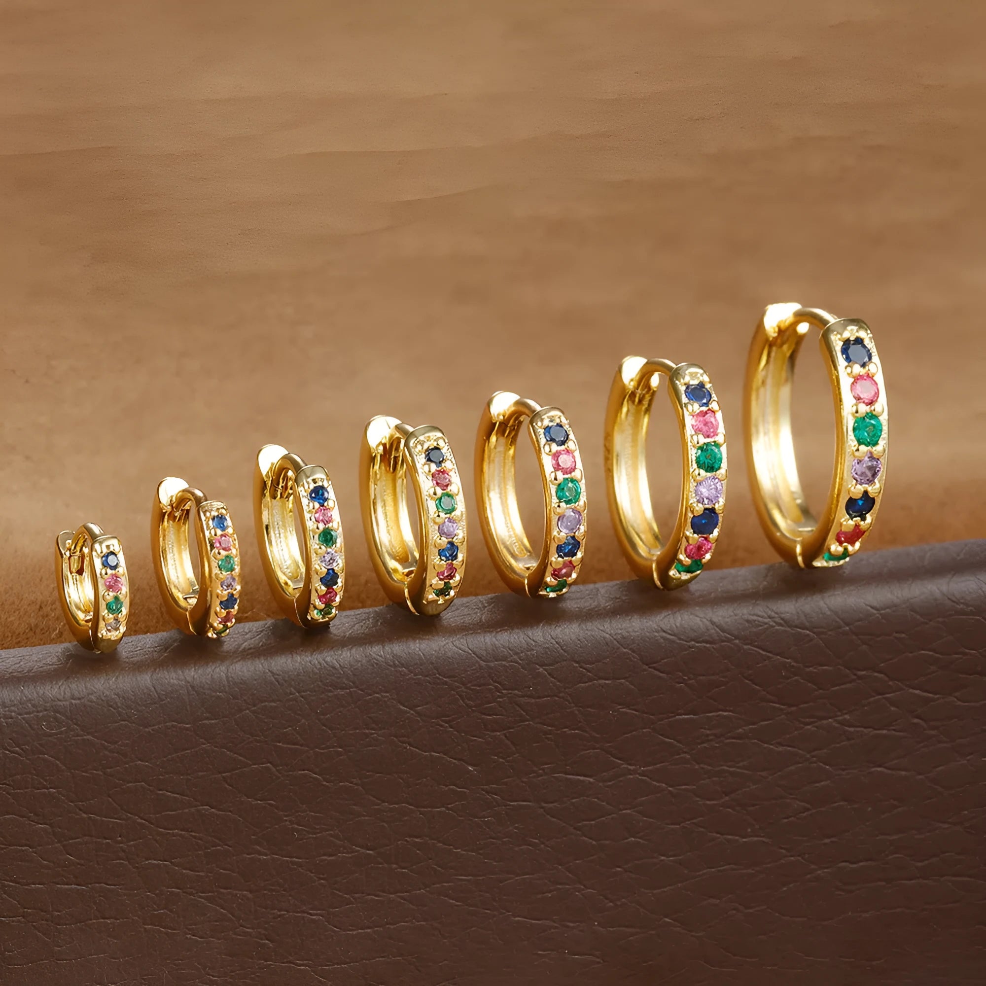 Gold, rose gold, and silver coloured circle-shaped zircon stud earrings on a white background.