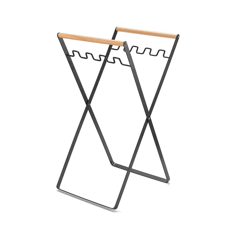 Black iron folding storage rack with a wooden handle for hanging outdoor waste bags.