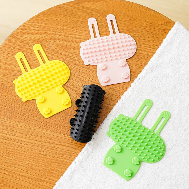 Silicone cat self-grooming brush with comb teeth and adjustable strap for table legs.