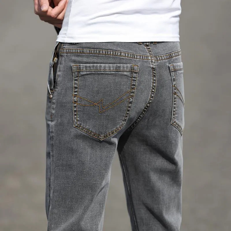 Man wearing smoky grey straight leg men's jeans with a low waist and zip fly.