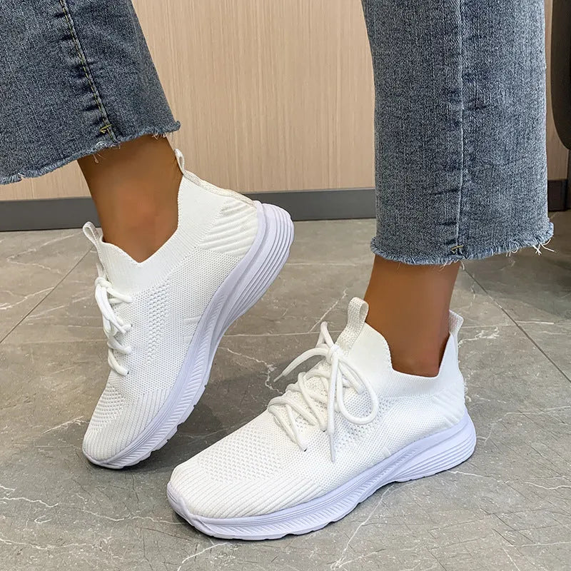 Women's mesh running shoes in creamy white with Flyknit upper and flat rubber sole