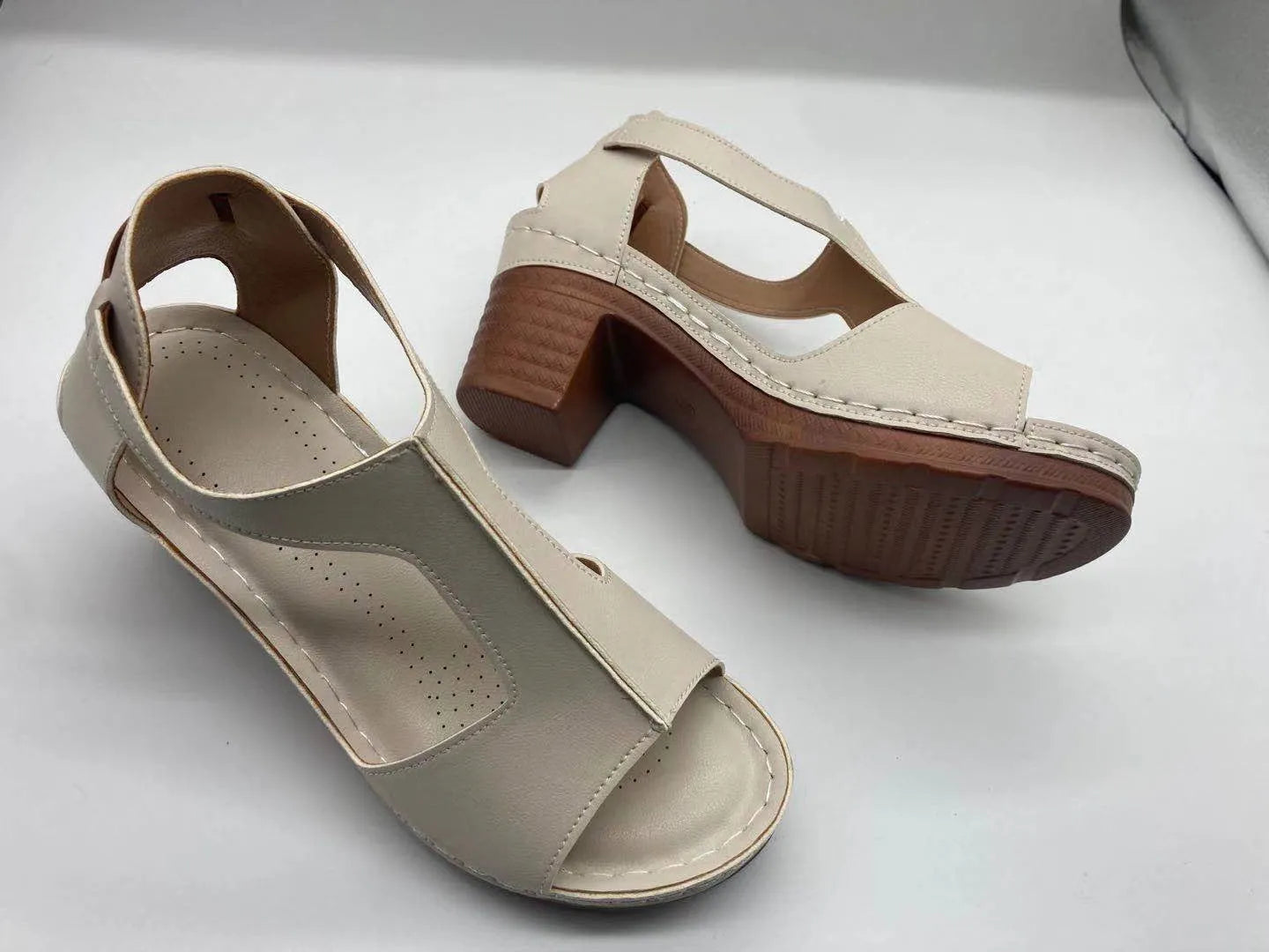 Plus size women's beige open toe wedge sandals with a buckle strap and low heel on a white background.