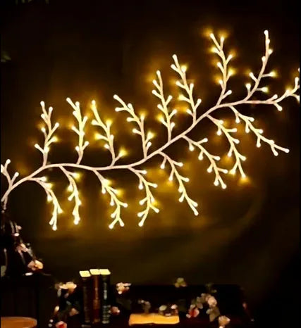 Flexible willow vine LED garland with birch bark texture and warm white lights shaped on a wall.