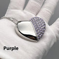 A heart-shaped silver USB flash drive with a brick pattern, shown next to a laptop.