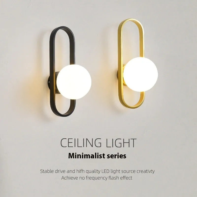 Minimalist modern wall lamp with glass shade and iron body in black finish, mounted on a wall.