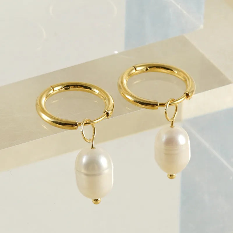 Geometric gold-coloured earrings with cultured pearl details on a white background.