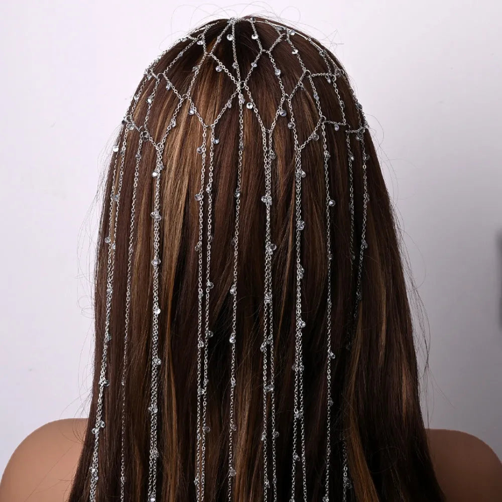Close-up of a gold metallic mesh headband with rhinestone details and hanging tassels.