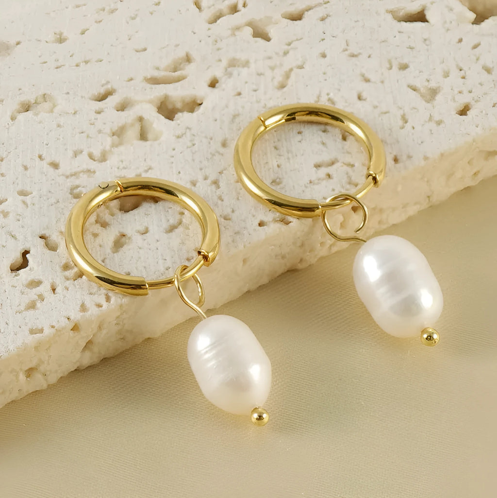 Geometric gold-coloured earrings with cultured pearl details on a white background.