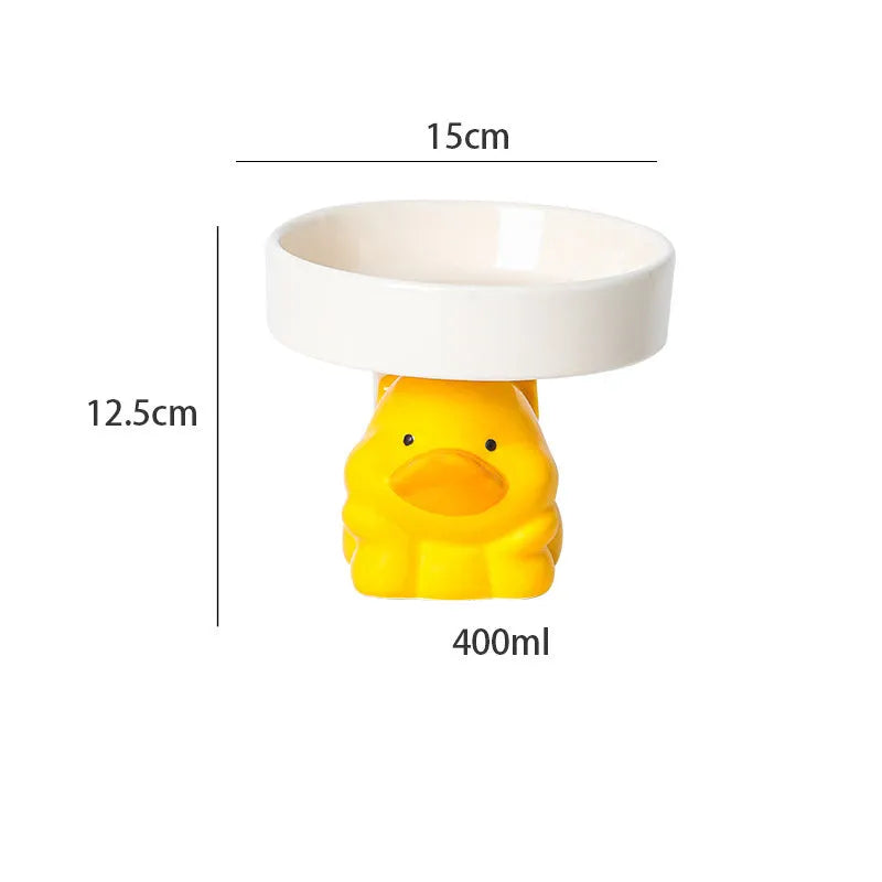 Raised ceramic cat bowl with animal design in pink, yellow, or white on a wooden floor.