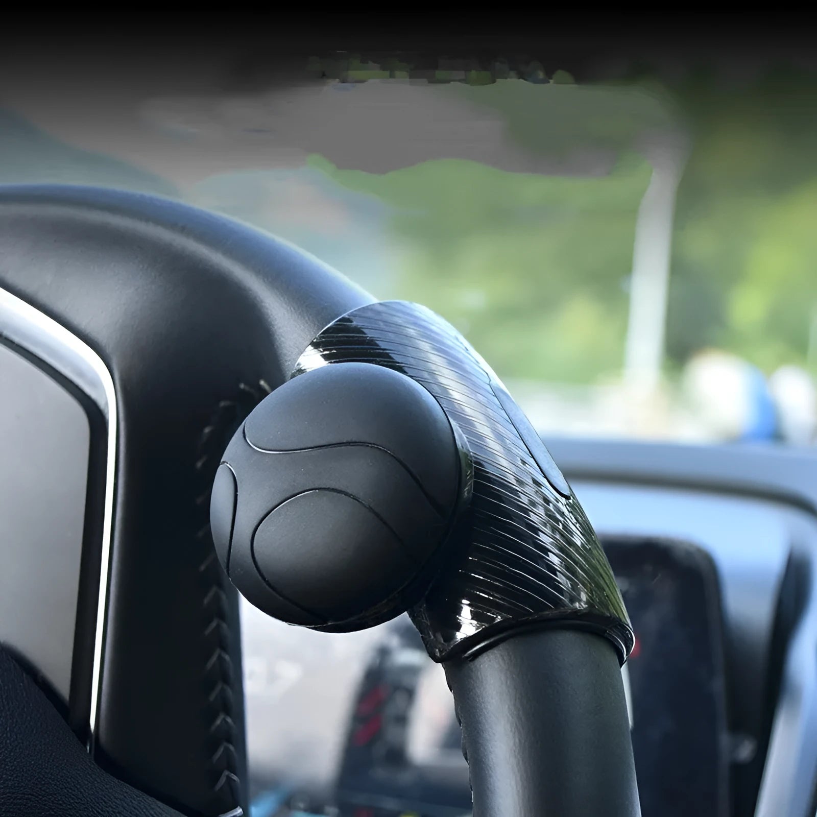 Black silicone steering wheel assist ball with metal bearing booster on a car steering wheel.