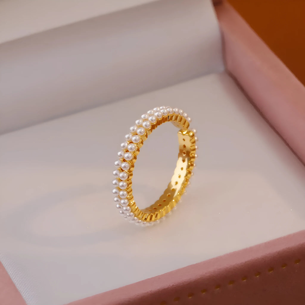 Gold-coloured women's open ring with geometric design and a round pearl-like bead.