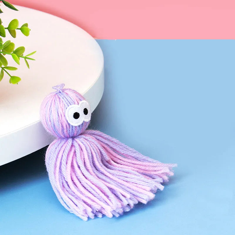 Blue grey wool ball cat toy with hanging loop next to a teaser stick.