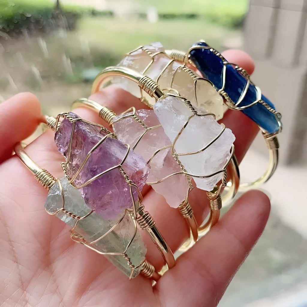 Gold winding geometric bracelet with unshaped rough natural crystal stones on a wrist.