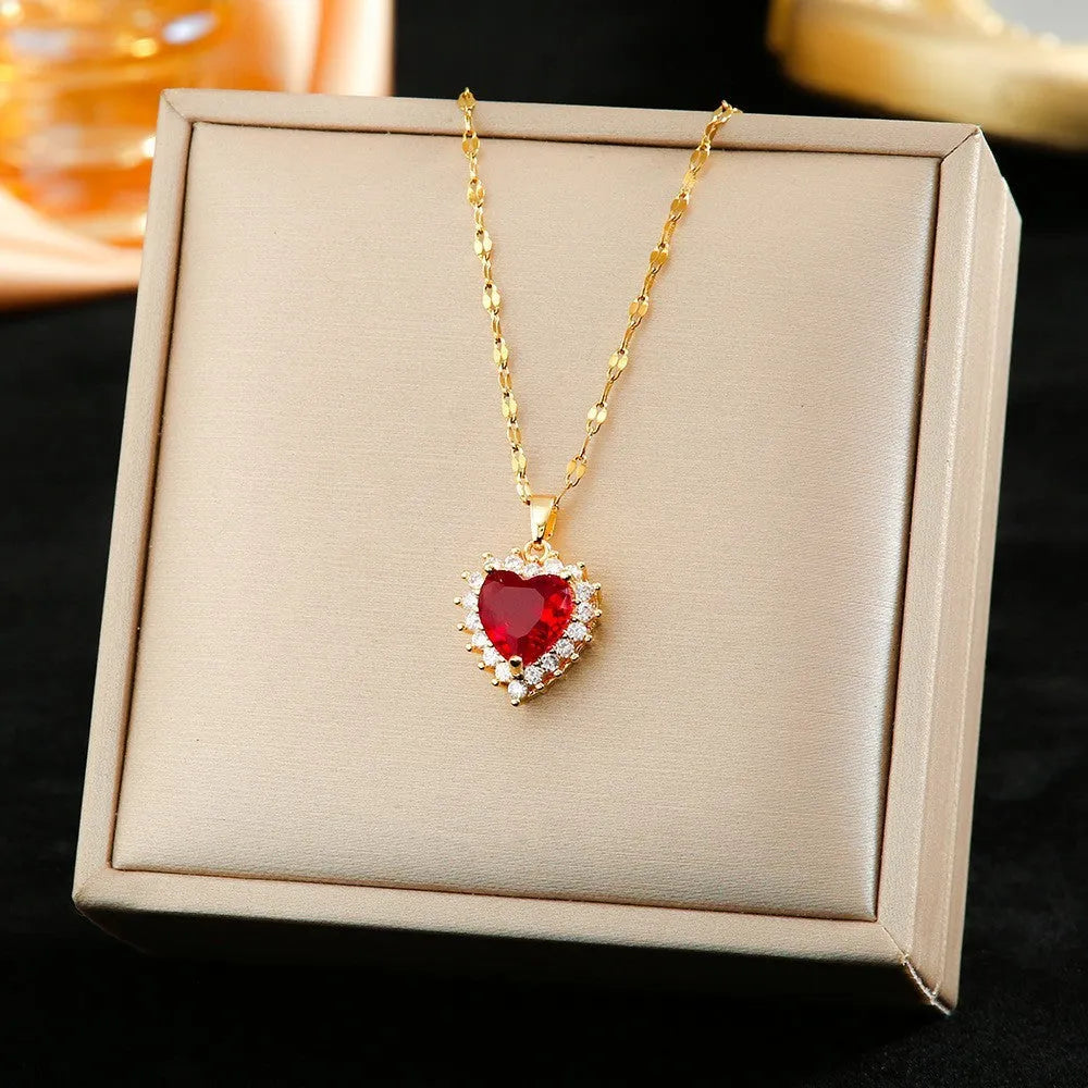 Gold red titanium steel heart jewellery set with gemstone inlay, showing necklace, earrings, and ring.