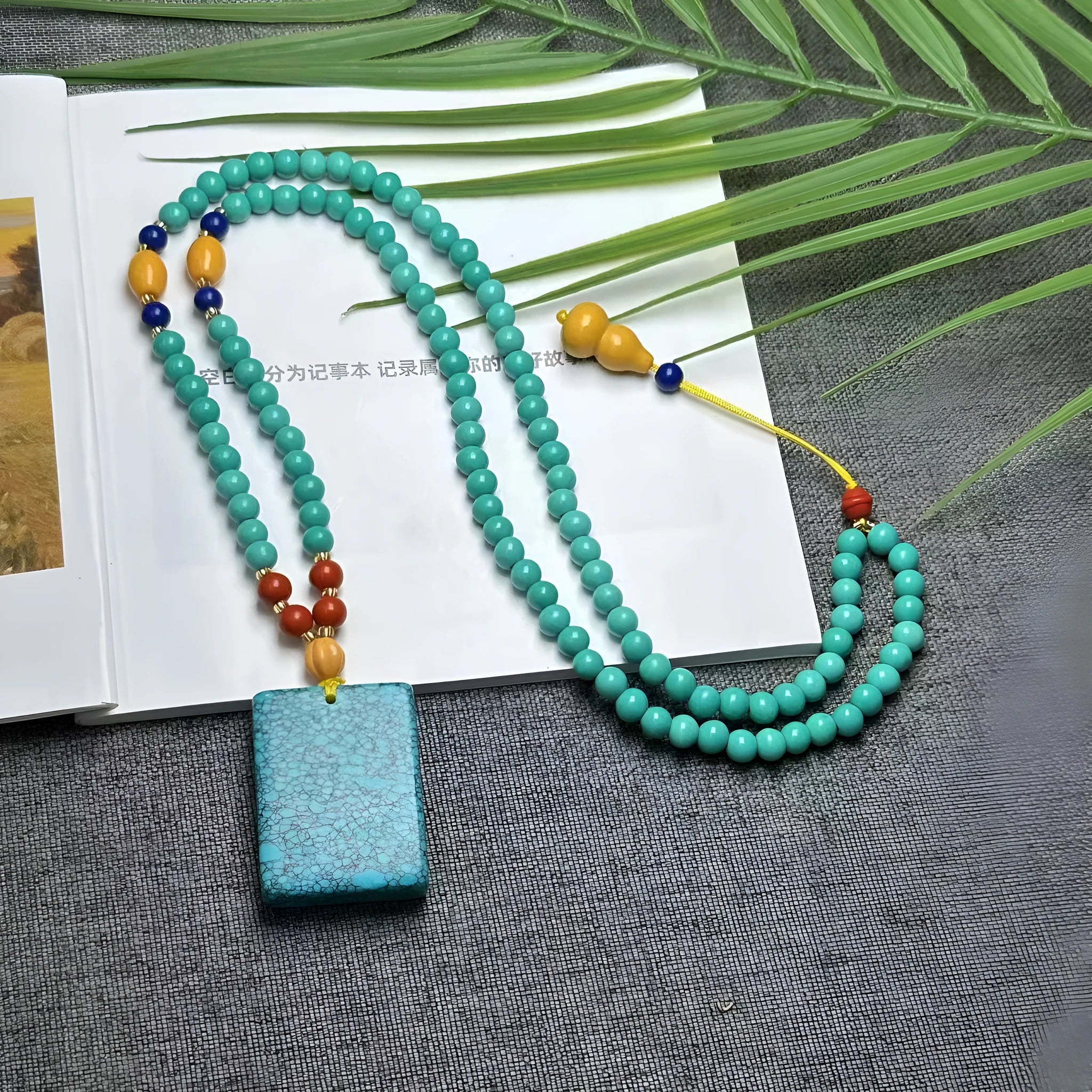 Hand-woven turquoise mesh flower lucky pendant on a ball bead necklace chain, adjustable length.