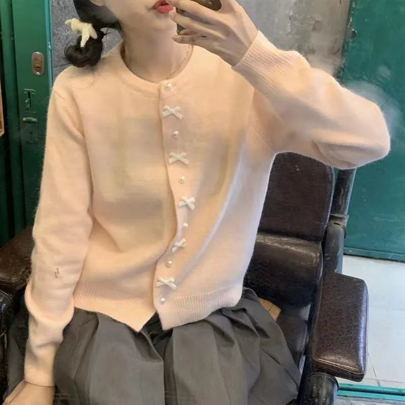 Women's solid colour cashmere cardigan with bow detail and pearl buttons on a hanger