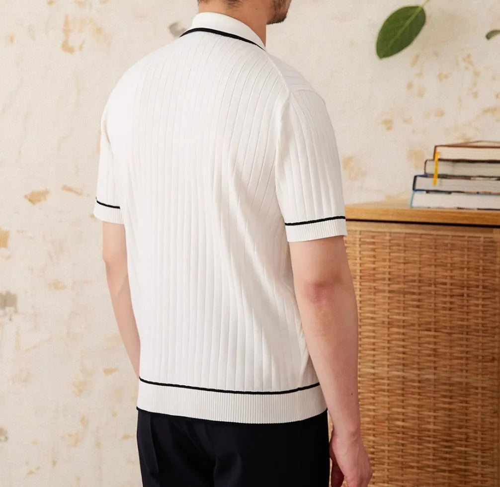 Man's slim fit black knitted polo shirt with lapel collar and short sleeves on a hanger.