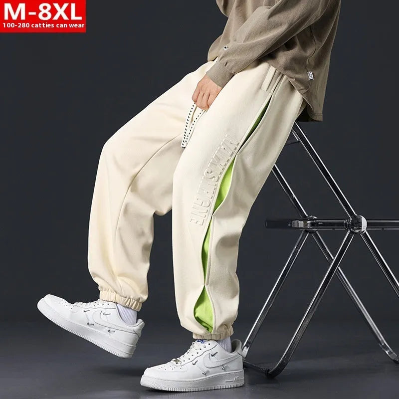 Man wearing loose grey-green trousers with stitching print detail and ankle banding.