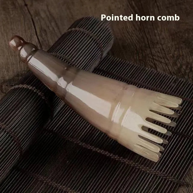 A white buffalo horn comb with wide teeth and a pointed tip for scalp massage.