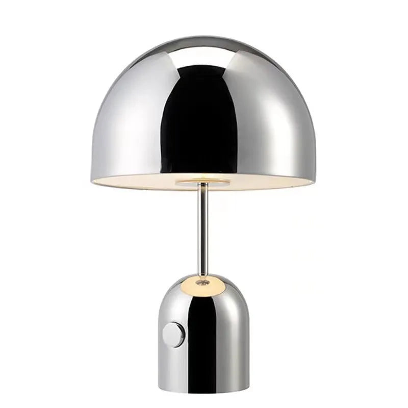 Mushroom shaped metal table lamp in rose gold finish on a wooden surface.