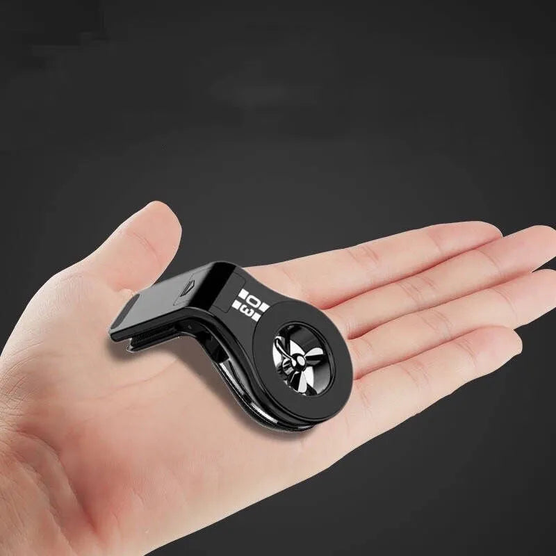 Black magnetic car phone holder clipped to a car air vent, showing a smartphone attached and the included fragrance slice.